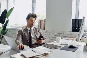Handsome young man busy working while sitting in office photo