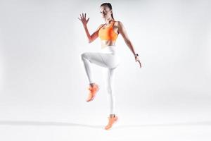 Hermosa mujer joven en ropa deportiva haciendo ejercicio contra el fondo blanco. foto