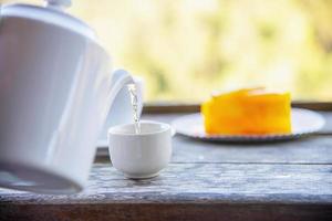 Hot eat cup and orange cake with green nature background - food and drink in wild nature concept photo