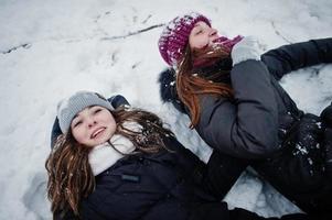 dos amigas divertidas divirtiéndose en el día de invierno cubierto de nieve cerca de árboles cubiertos de nieve. foto