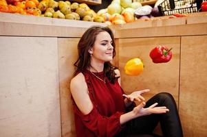 Girl in red throw peppers on fruits store. photo