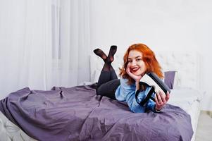 Red haired girl in bed with vr glasses at studio room. photo