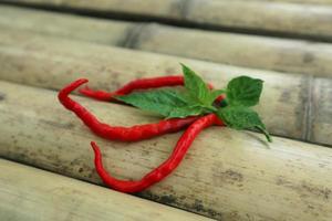 Hot chili peppers isolated on bamboo. Red and green Chile peppers plant photo