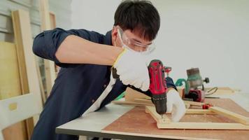 carpintero macho perforando agujeros en tablones de madera usando una máquina perforadora manual. concepto de carpintería, artesanía y trabajo manual video