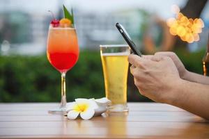 Man using mobile during happy time relax in restaurant with softdrink and green garden background - people relax with technology lifestyle concept photo