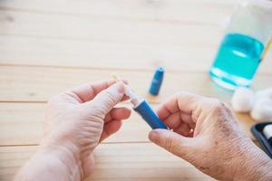 Old lady is testing blood sugar level using blood sugar test kid set - people with medical equipment concept photo