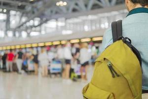 imagen de enfoque suave del viajero sobre una larga cola de pasajeros borrosa esperando el check-in en los mostradores de check-in del aeropuerto foto