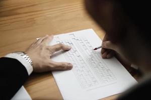 Instructor checking multiple choices answer sheet exam - education people working with paper test concept photo