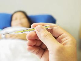 A doctor is looking at thermometer for measuring body temperature of his patient. Photo is focused at thermometer.