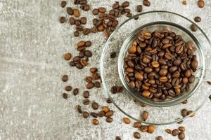 Transparent coffee cup with roasted coffee beans on gray concrete backgfound with copy space. photo