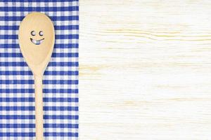 Kitchen mockup. Wooden spoon with smile on white wooden background. Food background with copy space photo