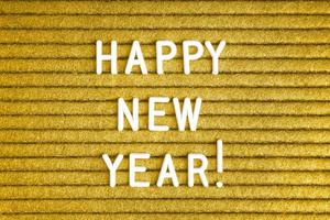 feliz año nuevo, texto en tablero de letras de fieltro amarillo con letras blancas foto