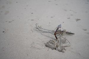 A small anchor rusted on the sand Of the beach by the sea photo