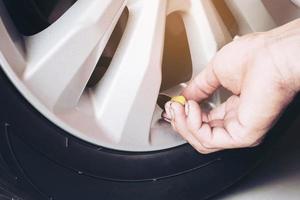 Hand is removing a green tire valve caps for nitrogen tire inflation service - car maintenance safety transportation concept photo