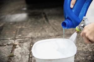 el hombre prepara agua con champú para lavar el auto usando - concepto de limpieza de autos para la gente del hogar foto