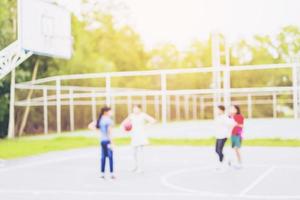 foto borrosa de niños asiáticos jugando baloncesto con luz solar cálida desde la esquina superior derecha
