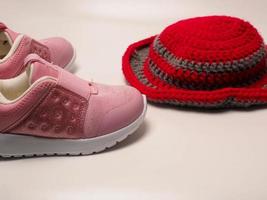 Picture of red color with grey stripes crochet hat and a pair of pink shoes photo