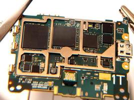 Close up shoot of printed circuit board PCB sitting on a white repair stand with magnifier for better examining small parts photo
