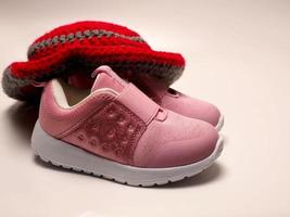 Picture of red color with grey stripes crochet hat and a pair of pink shoes photo