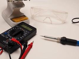 imagen de herramientas de reparación electrónica, compuesta por soporte para pcb, soldador, multímetro y gafas protectoras foto
