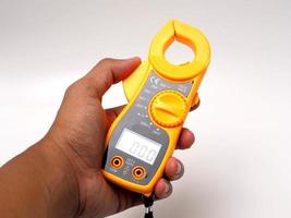 Picture of yellow digital clamp meter that using for measuring electrical current, voltage and resistance photo