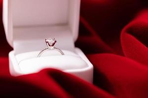 anillo de bodas de diamantes tela roja foto