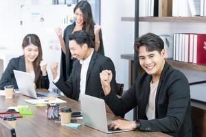 sí empresarios triunfando por el crecimiento financiero de la empresa. felices empresarios sonrientes triunfando con los puños levantados. foto