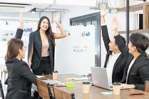 gente de negocios feliz en la computadora celebrando el éxito en el trabajo sentado en la oficina moderna. negociaciones exitosas. equipo de negocios mirando el monitor de la computadora. foto