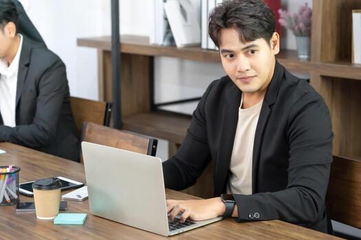 retrato de hombre de negocios usando computadora en el lugar de trabajo en una oficina. hombre de negocios positivo sonriendo mirando a la pantalla de la computadora. foto