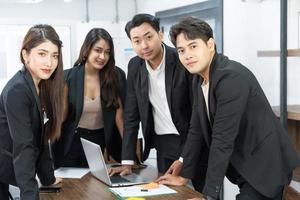 un equipo de negocios asiático confiado se encuentra en el cargo. la gente del equipo de oficina multicultural profesional feliz recomienda la mejor empresa. de pie juntos foto