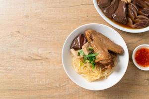 dried noodles with braised duck in white bowl photo