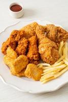 pollo frito con papas fritas y nuggets en un plato foto