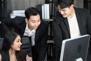 exitoso equipo empresarial multiedad de pie alrededor de la computadora para la presentación del trabajo. grupo de empresarios en una reunión en la oficina, trabajando en la computadora foto