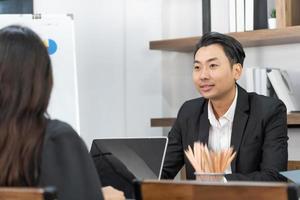 Group of business people working together, brainstorming in office. Smiling diverse businesspeople sit at office desk talk laugh discussing business ideas together, happy photo