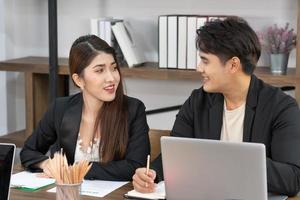 Group of business people working together, brainstorming in office. Smiling diverse businesspeople sit at office desk talk laugh discussing business ideas together, happy photo