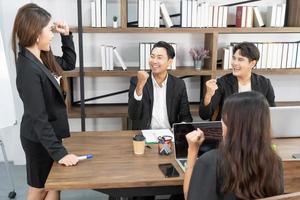 Group of business people working together, brainstorming in office. Smiling diverse businesspeople sit at office desk talk laugh discussing business ideas together, happy photo