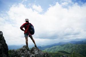 joven mujer de senderismo de pie en la roca superior, mujer mochila mirando el hermoso valle de montaña a la luz del sol en verano, paisaje con chica deportiva, colinas altas, bosque, cielo. viaje y Turismo. foto