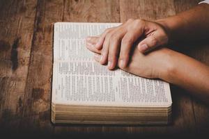 Close up of christian woman hand on holy bible are pray and worship for thank god in church with black background, concept for faith, spirituality and religion photo