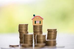 House model and money coins stacks with blur nature background. Savings plans for home, loan, investment, mortgage, finance and banking about house concept. photo