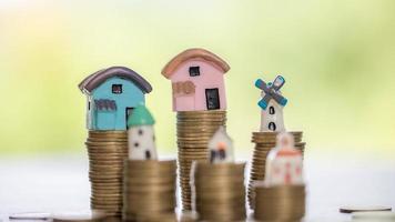 House model and money coins stacks with blur nature background. Savings plans for home, loan, investment, mortgage, finance and banking about house concept. photo