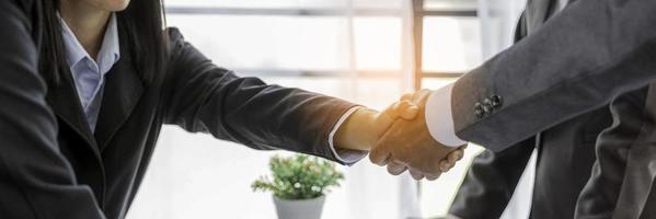 Professional businessman and businesswoman partners shaking hands together with business success deal and agreement. Hands business teamwork handshaking at office desk. Partnership banner copy space photo