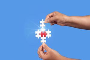 Hands holding jigsaw puzzles piece with clear blue background, success business, solution strategy, teamwork partnership concept photo