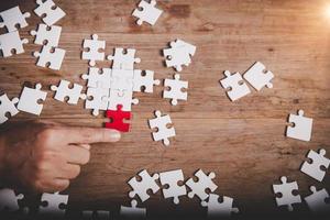 Hands holding jigsaw puzzles piece on wooden table background, success business, solution strategy, teamwork partnership concept photo