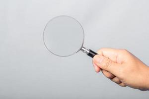 woman hand holding magnifying glass isolated on gray background. optical zoom lens is macro tool, concept for education, science. photo