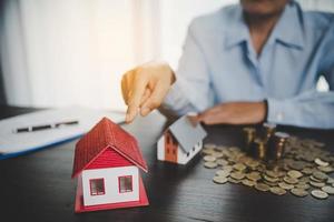 House model with stack coins, business hand is planning savings money of coins for buy home. concept for property ladder, mortgage with real estate investment and saving or investment for a house photo