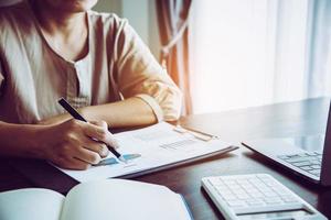 empresaria profesional que trabaja en el escritorio en la oficina. documento gráfico de análisis de mano de mujer de negocios financiero en papeleo con datos de gráfico e informe de crecimiento de marketing en la mesa. foto