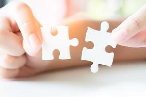 Close up hand holding and playing jigsaw game incomplete. White part of jigsaw puzzle pieces. concepts of problem solving, business, teamwork. photo