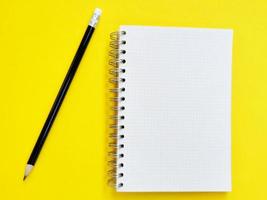 notebook and pencil on yellow background photo