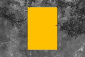maqueta de afiche cuadrado amarillo vacío con sombra clara sobre fondo de pared de hormigón negro. foto