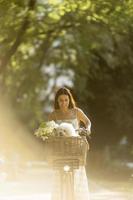 mujer joven con perro bichon frise blanco en la cesta de la bicicleta eléctrica foto